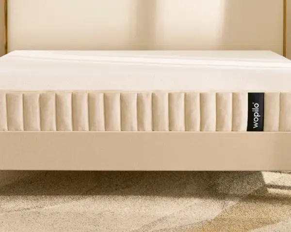 Un matelas hybride Wopilo sur un sommier beige aux pieds en bois. Quel sommier pour matelas hybride ? Ce lit offre un confort optimal.
