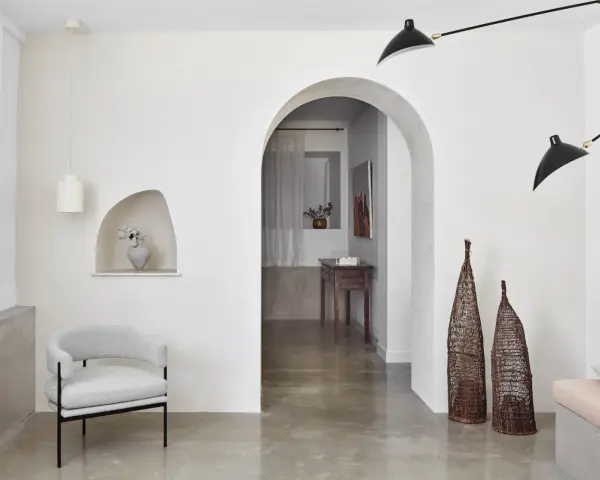 Un salon moderne avec un arche en pierre, un fauteuil gris, des lampes noires et un habillage arche maison.