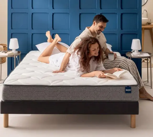 Un couple profite d'un moment de détente sur un matelas de taille lit 2 places. L'homme lit, la femme lit un livre.