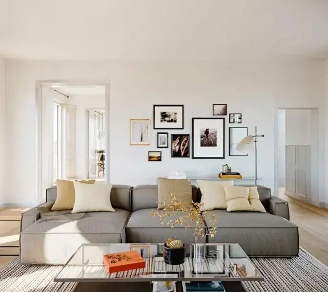 Un salon moderne avec un grand canapé gris, des coussins beiges et une galerie de cadres photo. Une excellente idée déco salon pour une ambiance chaleureuse.