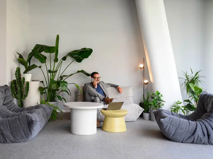 Un homme d'affaires au téléphone dans un coin salon moderne avec des plantes, une idée pour optimiser petit espace.