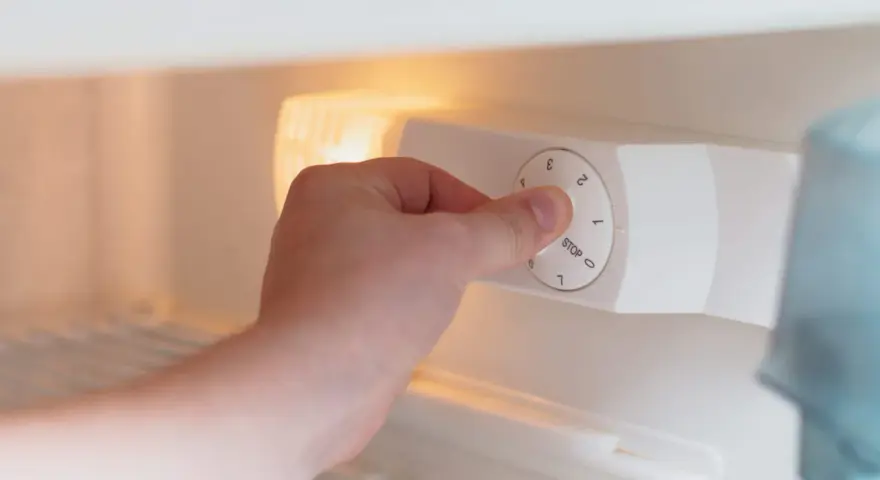 Main tenant ajuste la molette pour régler la quelle temperature congelateur. Le bouton indique "STOP" et des chiffres de 0 à 7.