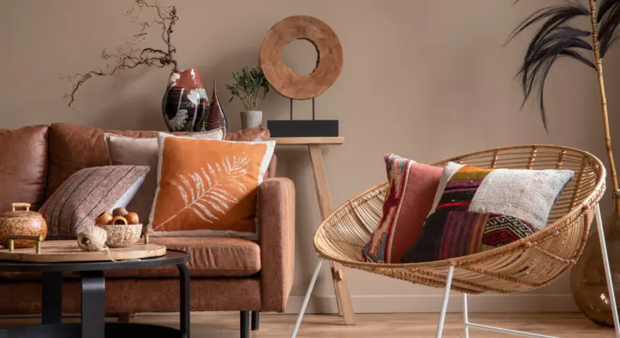 Un salon cosy avec un canapé en cuir marron, des coussins aux motifs ethniques et une chaise en rotin.