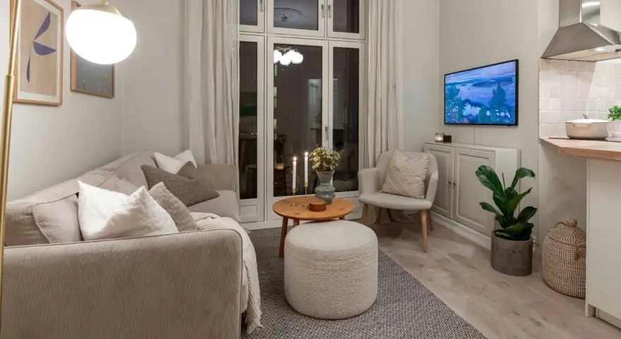 Salon cosy avec canapé, fauteuil, table basse et pouf. Une astuce rangement petit appartement : le meuble bas sous la TV optimise l'espace.