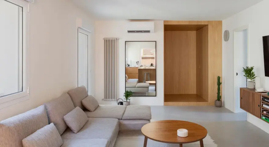 Salon épuré avec canapé modulable, table basse en bois et un coin boisé rappelant une maison style japonais en France.