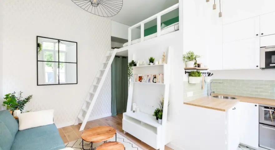 Plan studio 20m2 en longueur : canapé bleu, tables basses rondes, étagères, lit mezzanine accessible par échelle, cuisine compacte.