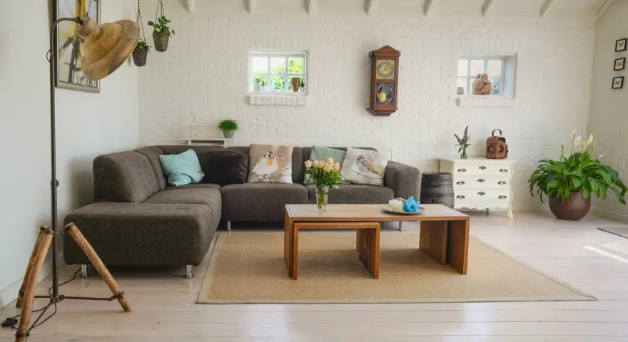 Un salon moderne avec poutre apparente, canapé confortable, table basse en bois et murs en briques blanches.