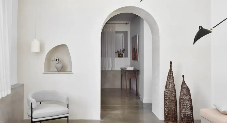 Un salon moderne avec un arche en pierre, un fauteuil gris, des lampes noires et un habillage arche maison.