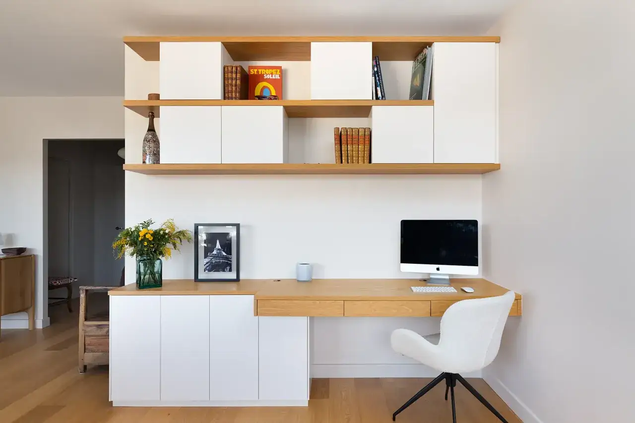 Un bureau moderne avec &eacute;tag&egrave;res en bois clair et rangements blancs. Un ordinateur, une chaise design et des livres cr&eacute;ent un espace de travail design inspirant.