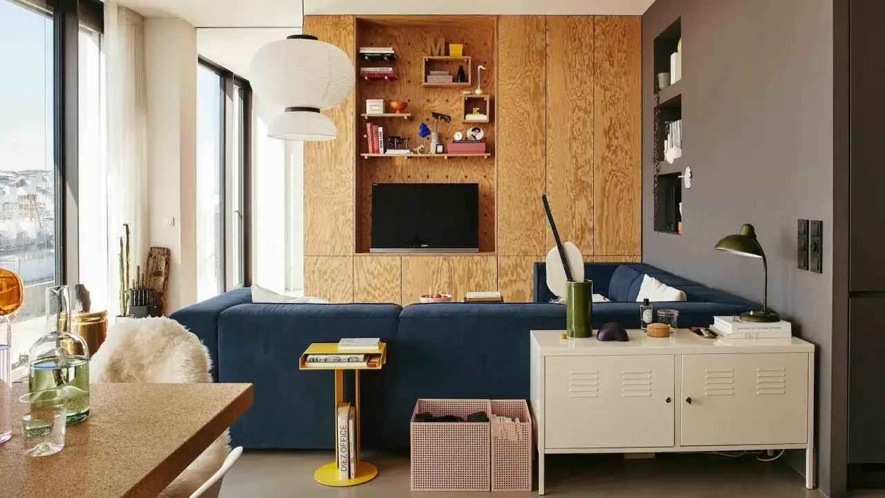 Un salon moderne avec un canap&eacute; bleu, des &eacute;tag&egrave;res en bois et des id&eacute;es pour comment agrandir une pi&egrave;ce.