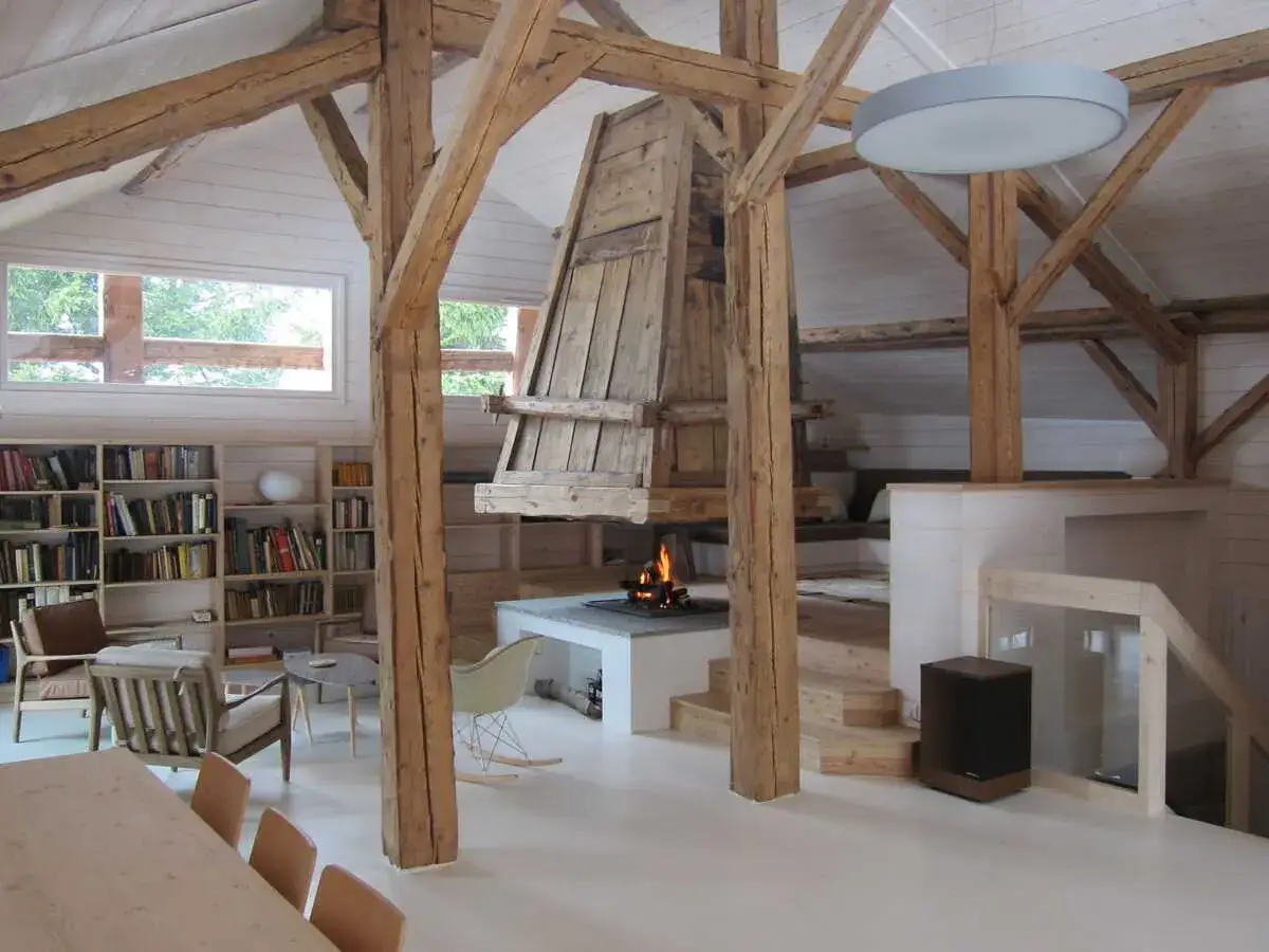 Ambiance chaleureuse dans un int&eacute;rieur ferme r&eacute;nov&eacute;e moderne. Poutres apparentes, chemin&eacute;e cr&eacute;pitante, et coin lecture cosy.