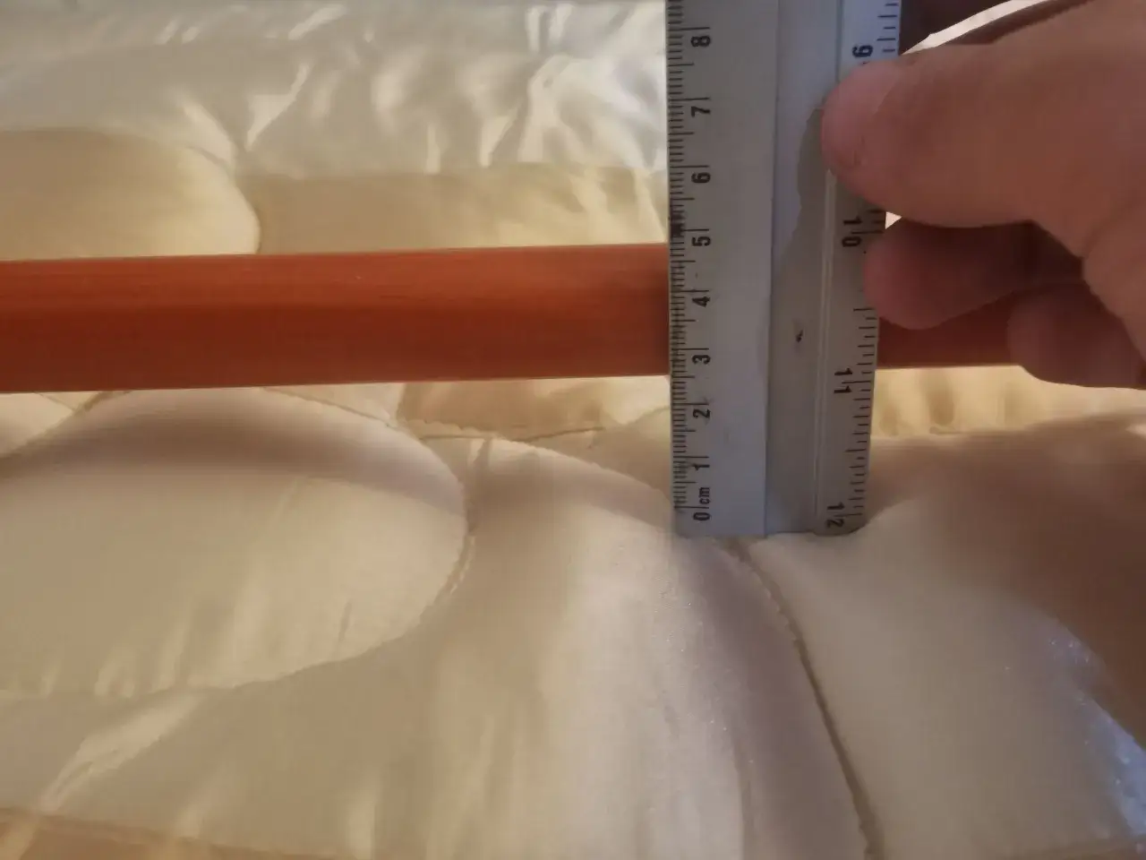 Une règle mesure la profondeur d'un creux sur un matelas neuf, soulevant la question : pourquoi mon matelas neuf se creuse ?