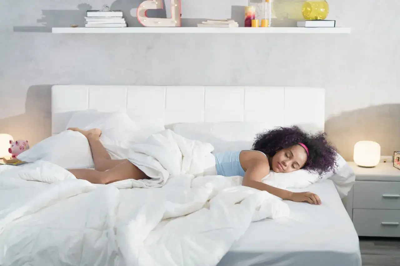 Une jeune femme dort paisiblement, profitant du confort de son lit. Une bonne nuit de sommeil dépend de la durée de vie d'un matelas.