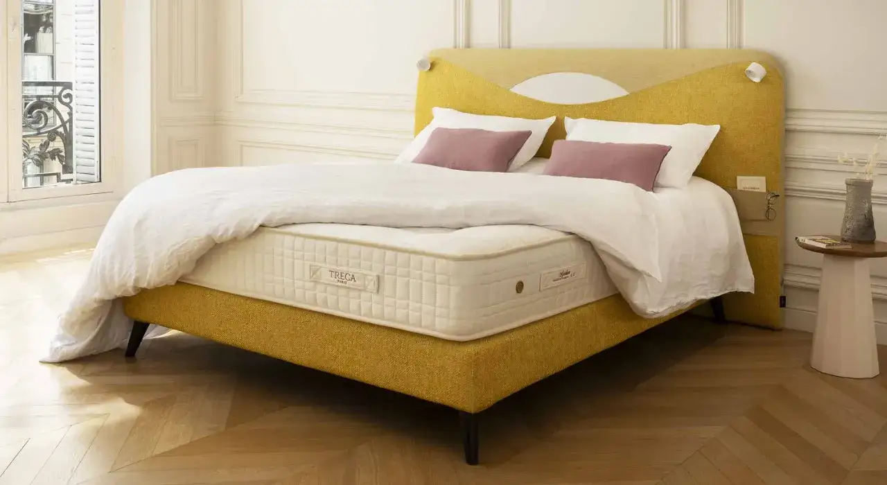 Un lit jaune moutarde avec un matelas Treca. Un surmatelas peut am&eacute;liorer le confort et la dur&eacute;e de vie de votre matelas.