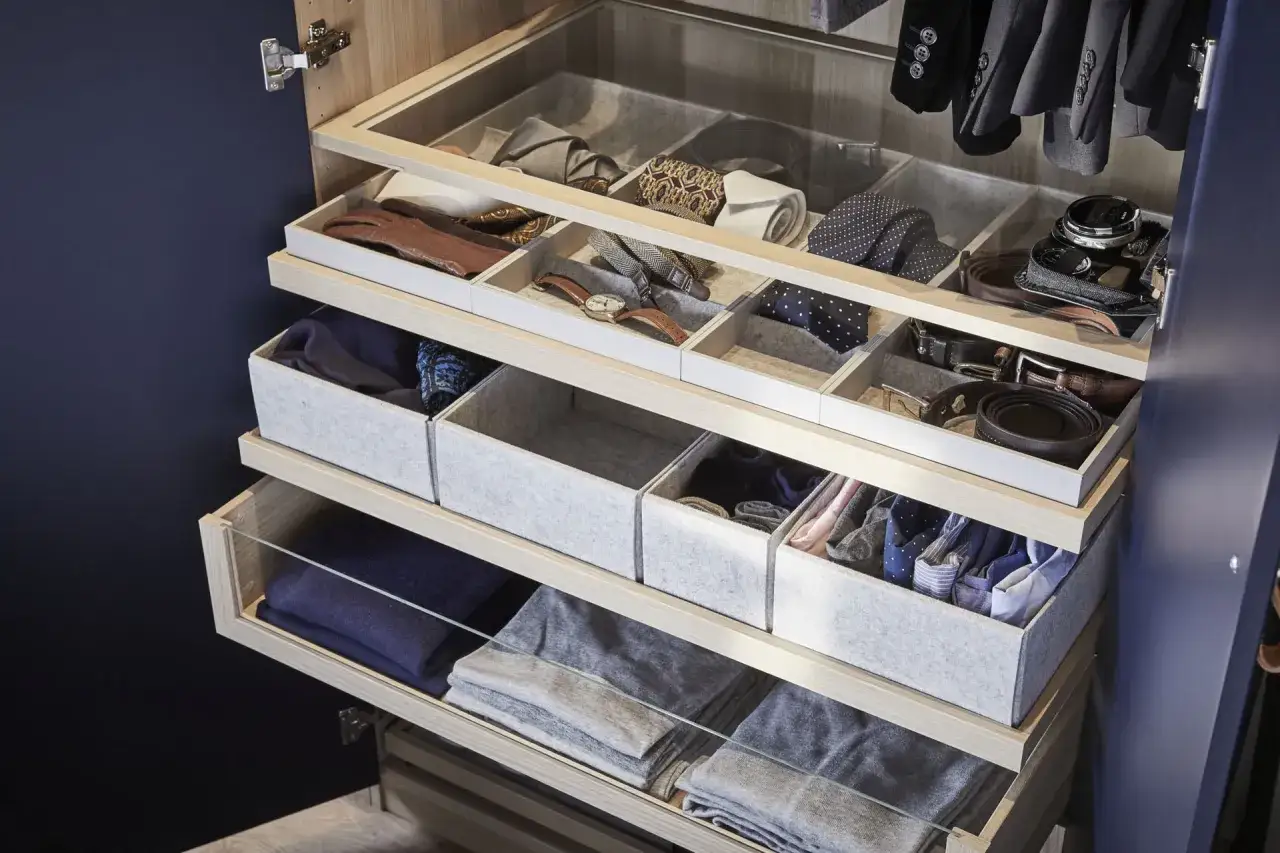 Un dressing bien organis&eacute; pour optimiser rangement v&ecirc;tements : cravates, ceintures, montres, gants et pulls pli&eacute;s dans des tiroirs et bo&icirc;tes.