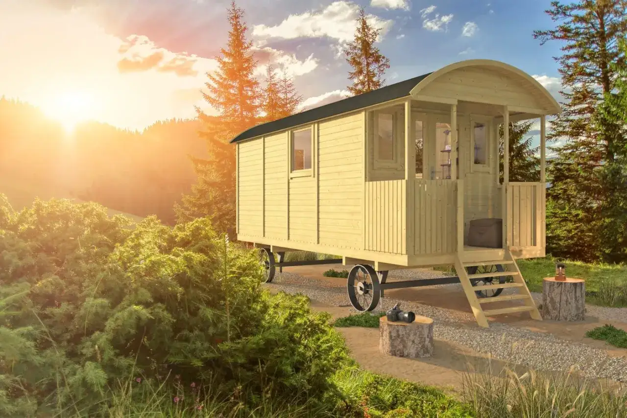 Une caravane transform&eacute;e en cabane en bois, nich&eacute;e dans un paysage verdoyant au coucher du soleil. Un refuge pittoresque pour les amoureux de la nature.