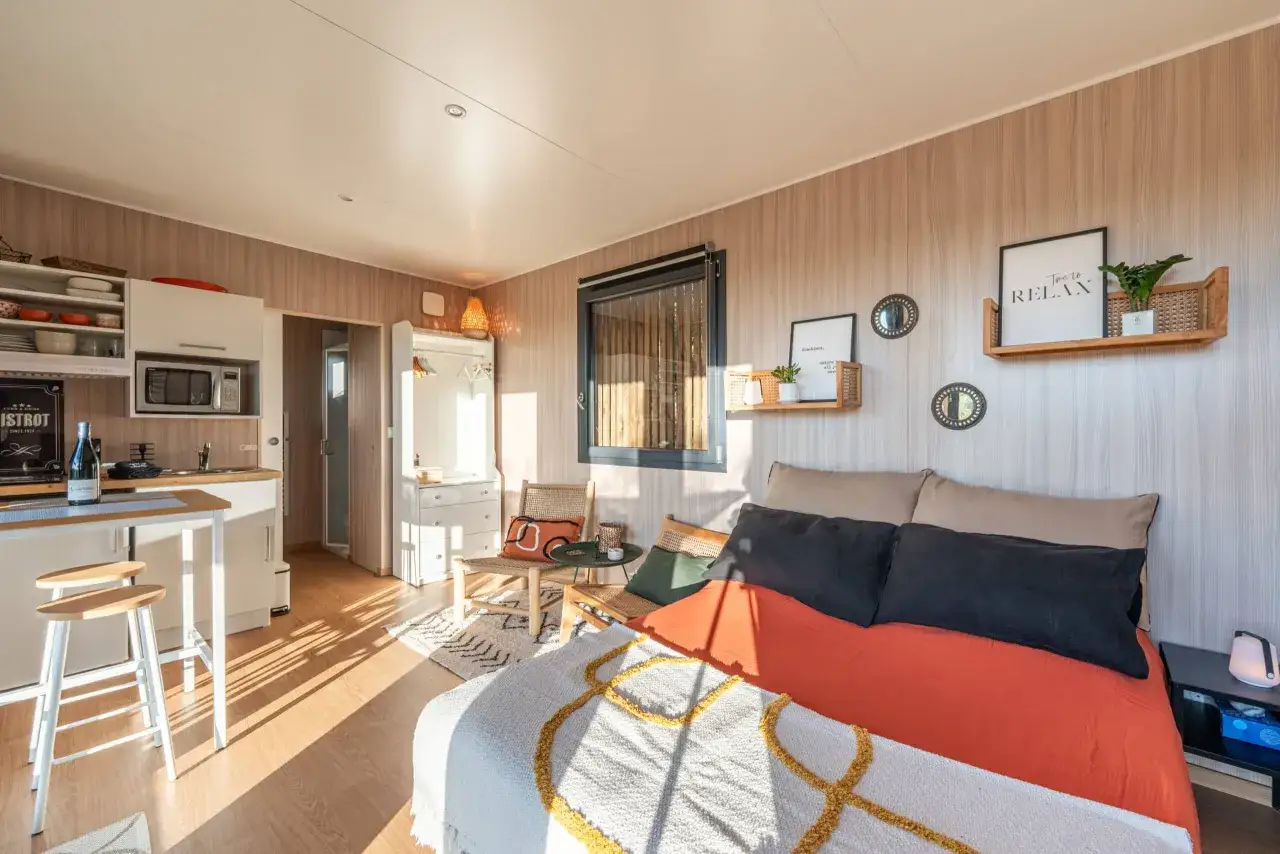 Plan studio 20m2 en longueur : cuisine, lit douillet, coin détente avec fauteuils en rotin. Décoration murale 