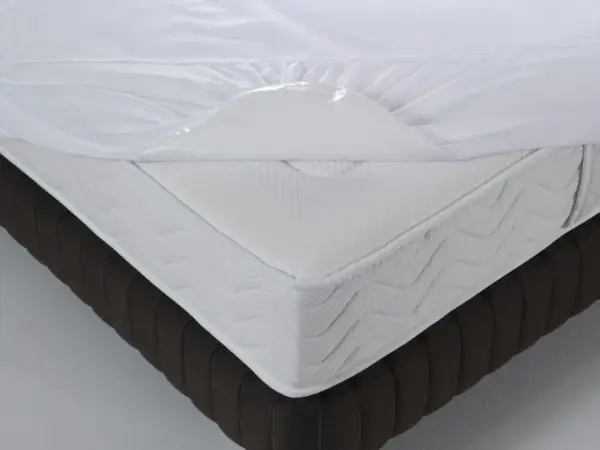 Un matelas blanc avec une alèse imperméable soulevée, montrant de quel côté mettre une alèse pour protéger le matelas.