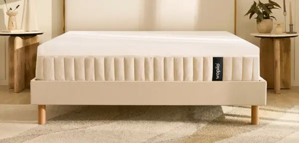 Un matelas hybride Wopilo sur un sommier beige aux pieds en bois. Quel sommier pour matelas hybride ? Ce lit offre un confort optimal.