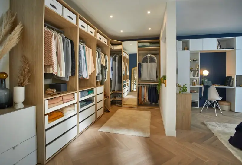 Un dressing DIY bien organisé avec des étagères en bois, des tiroirs blancs et des vêtements suspendus. Un espace fonctionnel pour ranger vos affaires.