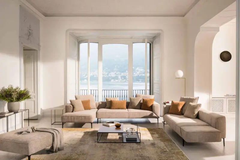 Un salon cocooning chaleureux avec un grand canapé d'angle, des coussins douillets et une vue imprenable sur un lac.