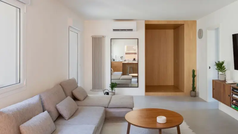 Salon épuré avec canapé modulable, table basse en bois et un coin boisé rappelant une maison style japonais en France.