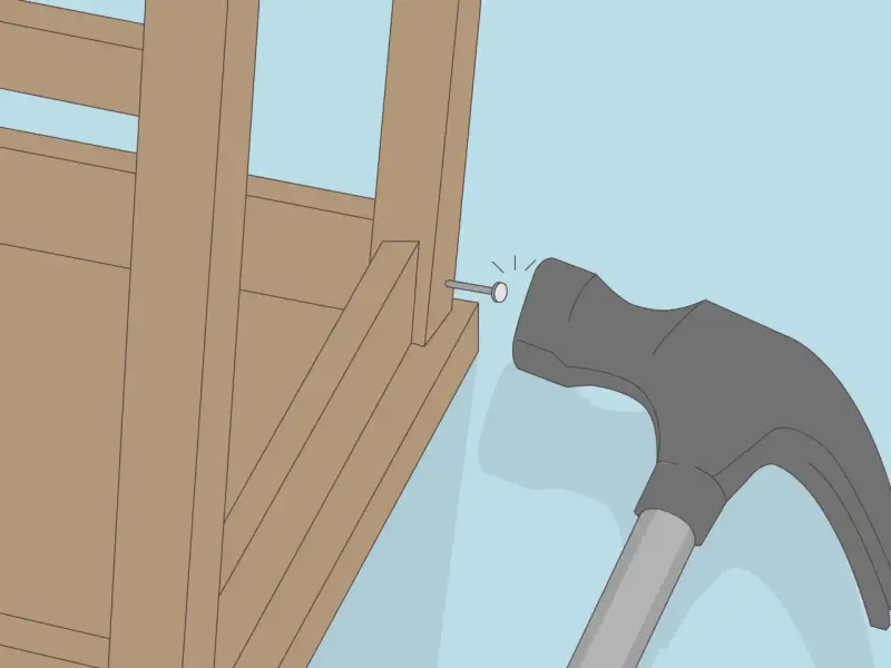 Un marteau s'apprête à frapper un clou dans la structure en bois d'un fauteuil qui grince.